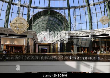 Glockenförmige goldene Weihnachtsdekorationen mit schönen kleinen warmen Lichtern im zentralen Bereich der Glaskuppel der Mall of the Emirates, Dubai, VAE. Stockfoto