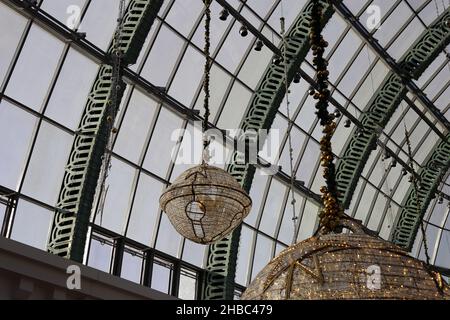 Glockenförmige goldene Weihnachtsdekorationen mit schönen kleinen warmen Lichtern im zentralen Bereich der Glaskuppel der Mall of the Emirates, Dubai, VAE. Stockfoto