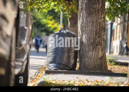 Stapel schwarzer Müllsäcke voller Müll, die auf der Straßenseite zur Abholung liegen. Abfallentsorgungskonzept. Stockfoto