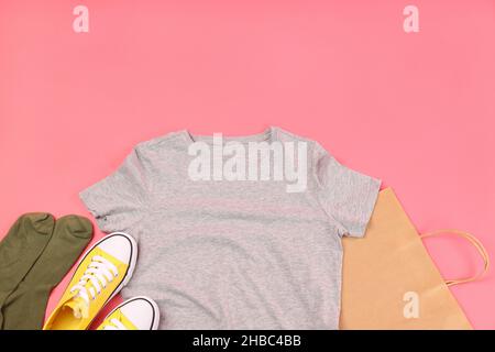 Leeres T-Shirt, Tasche, Sneaker und Socken auf rosa Hintergrund Stockfoto