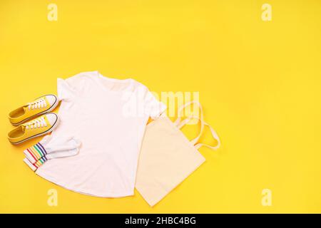 Leeres T-Shirt, Tasche, Socken und Sneakers auf gelbem Hintergrund Stockfoto