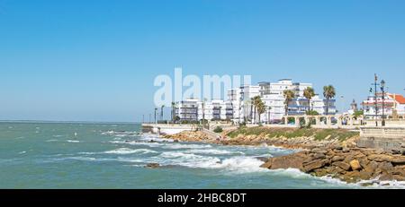 Wellen brechen auf den Felsen eines Strandes in Chipiona, Cádáz, Andalusien, Spanien Stockfoto