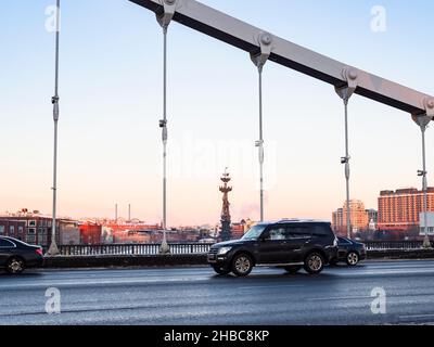 Moskau, Russland - 9. Dezember 2021: Die Autos auf der Krymskybrücke und das Denkmal Peter des Großen auf dem Moskwa-Fluss im Hintergrund in der Stadt Moskau am Abend t Stockfoto