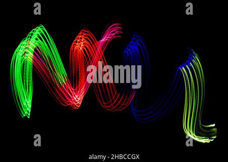 Light Neon Trails Bunte Welle isoliert auf schwarzem Hintergrund. Futuristisches, Farbenfrohes Overlay-Lichtmuster. Stockfoto
