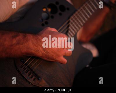 Nahaufnahme eines Mannes, der im Sonnenlicht Gitarre spielt Stockfoto