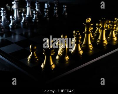 Eines Schachbretts mit silbernen und goldenen Figuren auf schwarzem Hintergrund Stockfoto