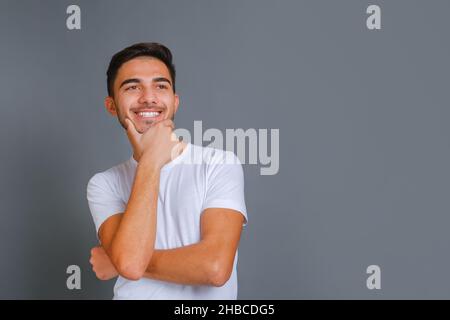 Lächelnder, gutaussehender Kerl, der unrasierte Kinn berührt Stockfoto