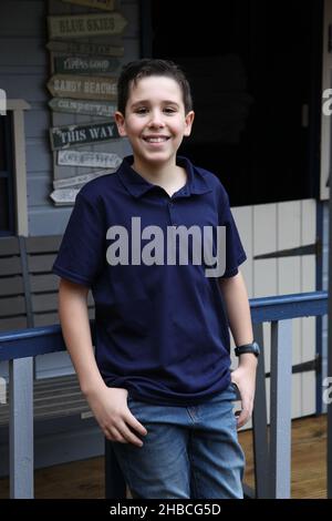 Ein Porträt eines 12-jährigen Jungen, der von Umgebungslicht durch ein Nebengebäude beleuchtet wird Stockfoto