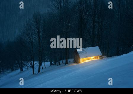 Nachtlandschaft mit einem Haus in einem winterverschneiten Wald Stockfoto