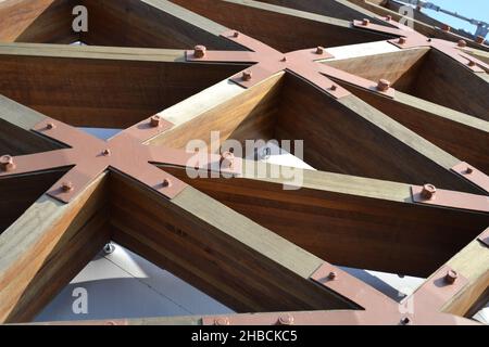 Nahaufnahme der stabilen dreieckigen Verriegelungsstruktur aus Holzbalken, die mit großen Eisenmuttern fixiert ist. Details. Stockfoto