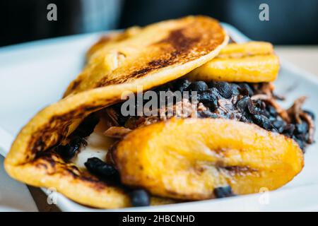 Venezolanischer Cachapa aus frittiertem Maisteig, gefüllt mit Schweinefleischspülungen und frischem Käse Stockfoto