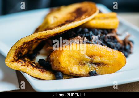 Venezolanischer Cachapa aus frittiertem Maisteig, gefüllt mit Schweinefleischspülungen und frischem Käse Stockfoto