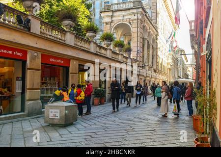 Hintergrundbeleuchtete Ansicht der Via Garibaldi mit Palazzo Doria-Tursi, Sitz des Rathauses von Genua, mit Menschen zu Fuß im Herbst und Streulicht, Ligurien, Italien Stockfoto