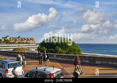 Menschen, die an einem sonnigen Herbsttag entlang der Strandpromenade des Corso Italia mit dem Lido-Gebäude spazieren, Genua, Ligurien, Italien Stockfoto