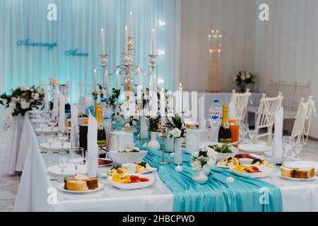 Hochzeitssaal mit Blumen dekoriert. Tisch bei einem luxuriösen Hochzeitsempfang. Serviert für Banketttische in luxuriösem Interieur. Stockfoto