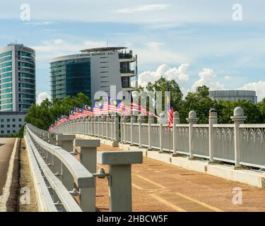 Putrajaya, Malaysia - 10. Sep 2021: Malaysische Flaggen, bekannt als Jalur Gemilang, winken auf der Brücke wegen der Feier des Unabhängigkeitstages oder des Merdeka-Tages Stockfoto