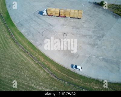 Geparkter LKW mit Heuballen Luftaufnahme mit kleinem Auto an einem Rastplatz auf der Straße, in der Nähe von Melbourne, Victoria, Australien. Stockfoto