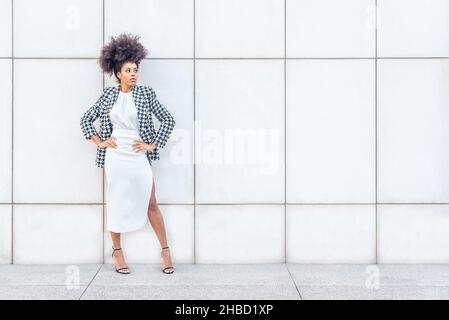 Frau in formeller Kleidung, die mit ihren Armen in Gläsern posiert Stockfoto
