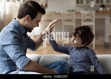 Überglücklich Vater und kleiner Sohn geben hohe fünf, feiern Erfolg Stockfoto