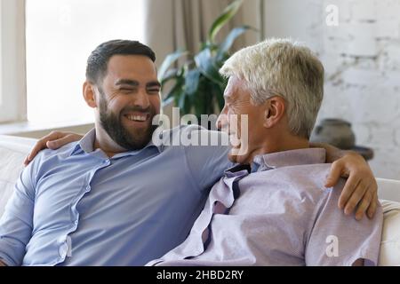 Glücklicher junger Mann, der zu Hause mit einem Vater mittleren Alters spricht. Stockfoto