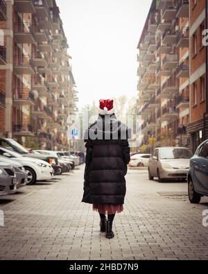 Frau geht während der Quarantäne mit Autos und Häusern im Hintergrund auf der Straße. Quarantäne in Georgien.Saburtalo. Urbaner Stadtleben im Winter 20 Stockfoto