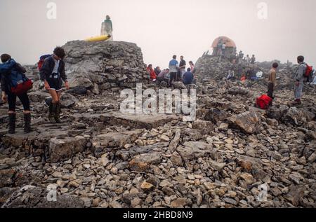 Archivbild Sommer 1988. Gruppen von Bergsteigern und Bergsteigern auf dem Gipfel des Ben Nevis, dem höchsten Berg Großbritanniens, in der Sommerwolke. Ein Kanu wurde auf den Berg gebracht und auf einer Kaira (links in der Mitte) aufgestellt. Stockfoto