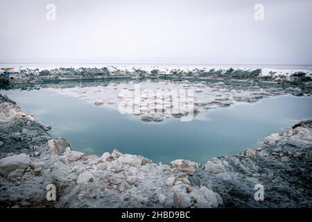 Salzwasserteich mit natürlich bildenden Salzkristallen in der Mitte und Salzwasser rund um nach Regen im See von Tuz in der Türkei. Stockfoto