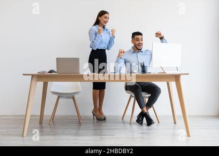 Mitarbeiter, die ein Notebook verwenden, feiern den Erfolg und schütteln die Fäuste mit Ja Stockfoto