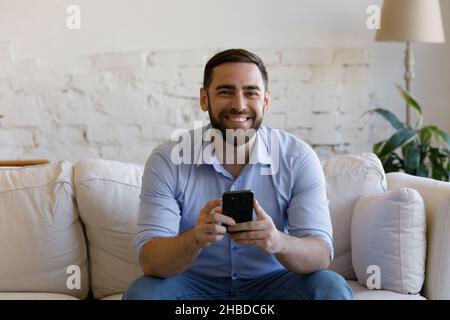 Porträt eines lächelnden jungen Mannes mit Smartphone in den Händen. Stockfoto