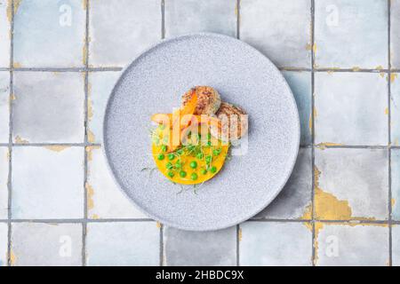 Hühnerschnitzel mit Kürbispüree und grünen Pasteten, verziert mit Karotten auf Fliesenhintergrund Stockfoto