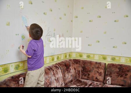 Boy zeichnet an den Wänden. Kind hat Spaß und Flecken an der Wand Stockfoto