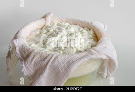 Ein Durcheinander von fermentiertem Käse oder Quark oder griechischem Joghurt auf einem Waffeltuch, um ihn von der Molke zu trennen Stockfoto