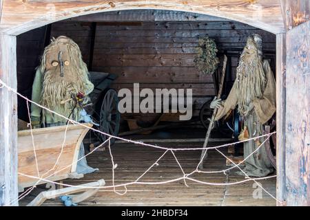 Puppen in Meteņi Mumming Masken und Kostüme von alten Männern, die in alten hölzernen Karren-Haus Stockfoto