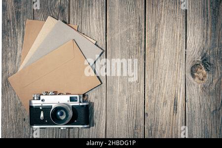 Vintage Retro-Kamera und Briefumschläge mit Buchstaben auf Holzhintergrund, flach liegend. Stockfoto