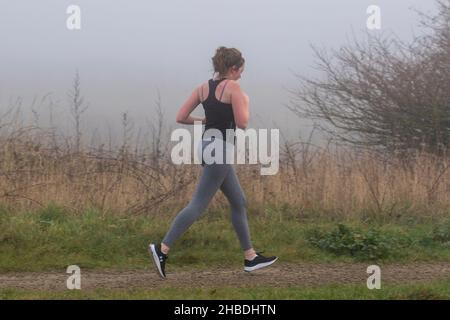 Southport, Merseyside. Wetter in Großbritannien; 18th. Dezember 2021. Dichter Nebel nach der kältesten Nacht des Jahres in der nordwestlichen Küstenstadt. Die Bewohner des Resorts können bei kalten, nebligen Bedingungen morgens an der Strandpromenade leichte Übungen machen. Kredit; MediaWordImages/AlamyLiveNews Stockfoto