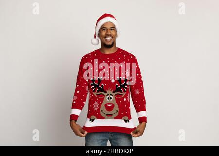 Glücklicher afroamerikanischer Kerl, der seinen Pullover mit Hirsch zeigt Stockfoto