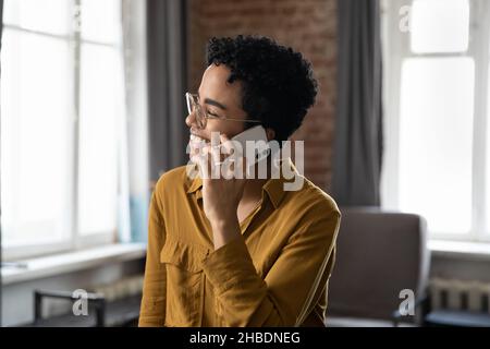 Glücklich lachende tausendjährige afroamerikanische Frau hält Telefongespräch. Stockfoto