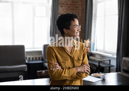 Lächelnd motivierte junge afroamerikanische Geschäftsfrau, die in der Ferne schaute. Stockfoto