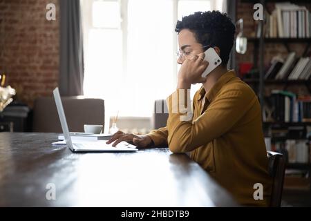 Konzentrierte junge afroamerikanische Frau, die im Büro multitasking. Stockfoto