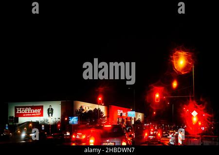 Berlin, Deutschland - 18. Dezember 2021: Nachtaufnahme einer Kreuzung im Regen mit einem Möbelgeschäft im Hintergrund. Die Lichter erscheinen surreal durch t Stockfoto