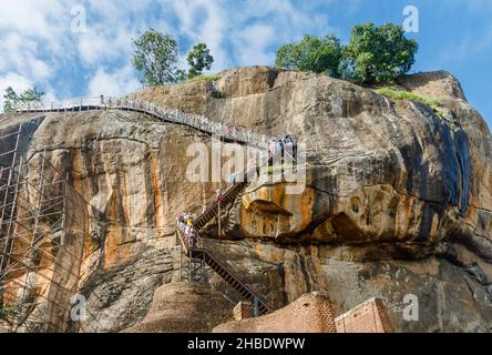 Touristen klettern die Löwentreppe Zugang zum Rock Top Palace bei Sigiriya (Lion Rock), Sri Lanka Kulturdreieck, eine historische Monument Attraktion Stockfoto