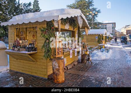 Belluno, Italien - Dez 11 2021. Traditionelle Weihnachtsmarktstände auf der Piazza dei Martiri im historischen Zentrum. Covid-bezogene Schilder befinden sich an den Ständen Stockfoto