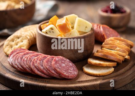 Snack-Platte mit in Scheiben geschnittenen Salami, Creackern, gerösteten Runden und Käsewürfeln in einer Schüssel Stockfoto