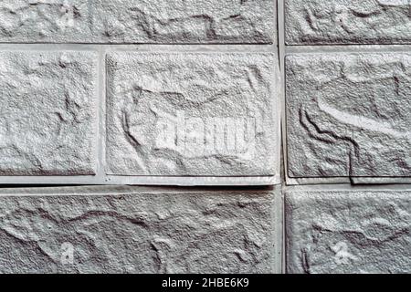 Die Tapete beginnt sich abzulösen. Die Tapete aus alten weißen Ziegeln schälte sich von der Wand im Raum, weil es feucht war oder sich nicht gut klebte. Reparieren Sie A Stockfoto