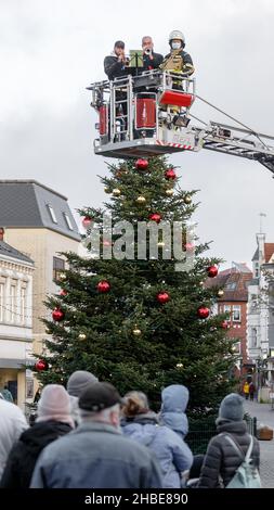 Barmstedt, Deutschland. 19th Dez 2021. Zwei Trompeter spielen Weihnachtslieder neben einem Feuerwehrmann im Korb einer Drehteller-Feuerwehrleiter auf dem Marktplatz in Barmstedt. Auch andere Feuerwehren im Kreis Pinneberg machen heute so Musik und werden gemeinsam eine gemeinsame Weihnachtsbotschaft aus Videoaufnahmen bearbeiten. Quelle: Markus Scholz/dpa/Alamy Live News Stockfoto