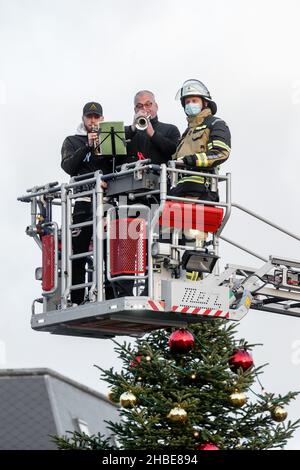 Barmstedt, Deutschland. 19th Dez 2021. Zwei Trompeter spielen Weihnachtslieder neben einem Feuerwehrmann im Korb einer Drehteller-Feuerwehrleiter auf dem Marktplatz in Barmstedt. Auch andere Feuerwehren im Kreis Pinneberg machen heute so Musik und werden gemeinsam eine gemeinsame Weihnachtsbotschaft aus Videoaufnahmen bearbeiten. Quelle: Markus Scholz/dpa/Alamy Live News Stockfoto