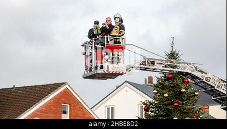 Barmstedt, Deutschland. 19th Dez 2021. Zwei Trompeter spielen Weihnachtslieder neben einem Feuerwehrmann im Korb einer Drehteller-Feuerwehrleiter auf dem Marktplatz in Barmstedt. Auch andere Feuerwehren im Kreis Pinneberg machen heute so Musik und werden gemeinsam eine gemeinsame Weihnachtsbotschaft aus Videoaufnahmen bearbeiten. Quelle: Markus Scholz/dpa/Alamy Live News Stockfoto