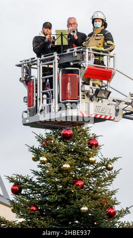 Barmstedt, Deutschland. 19th Dez 2021. Zwei Trompeter spielen Weihnachtslieder neben einem Feuerwehrmann im Korb einer Drehteller-Feuerwehrleiter auf dem Marktplatz in Barmstedt. Auch andere Feuerwehren im Kreis Pinneberg machen heute so Musik und werden gemeinsam eine gemeinsame Weihnachtsbotschaft aus Videoaufnahmen bearbeiten. Quelle: Markus Scholz/dpa/Alamy Live News Stockfoto