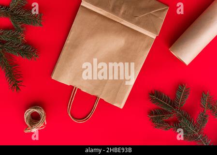 Weihnachten und Neujahr festlich Flat Lay imitieren Geschenke Herstellung, Vorbereitung und Verpackung in Kraftpapier-Paket auf rotem Hintergrund. Stockfoto