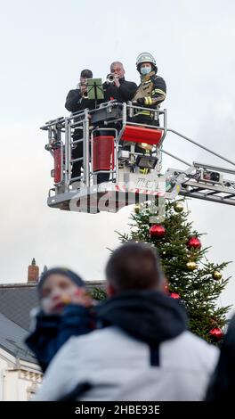 Barmstedt, Deutschland. 19th Dez 2021. Zwei Trompeter spielen Weihnachtslieder neben einem Feuerwehrmann im Korb einer Drehteller-Feuerwehrleiter auf dem Marktplatz in Barmstedt. Auch andere Feuerwehren im Kreis Pinneberg machen heute so Musik und werden gemeinsam eine gemeinsame Weihnachtsbotschaft aus Videoaufnahmen bearbeiten. Quelle: Markus Scholz/dpa/Alamy Live News Stockfoto